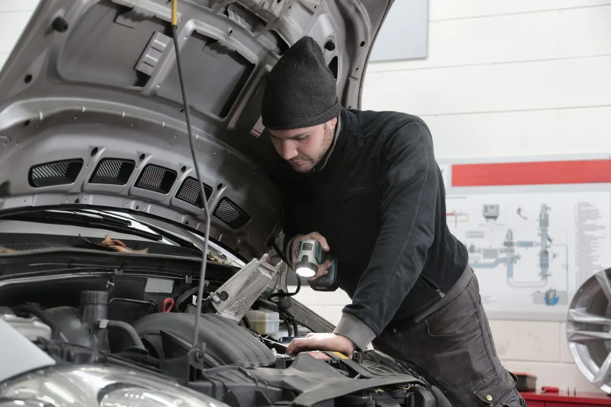 Mechanic inspecting a car with a torch for a Nuneaton customer