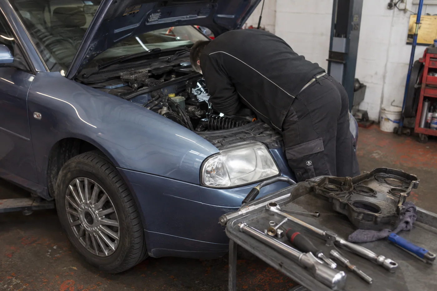Mechanic carrying out timing belt work in an open engine bay